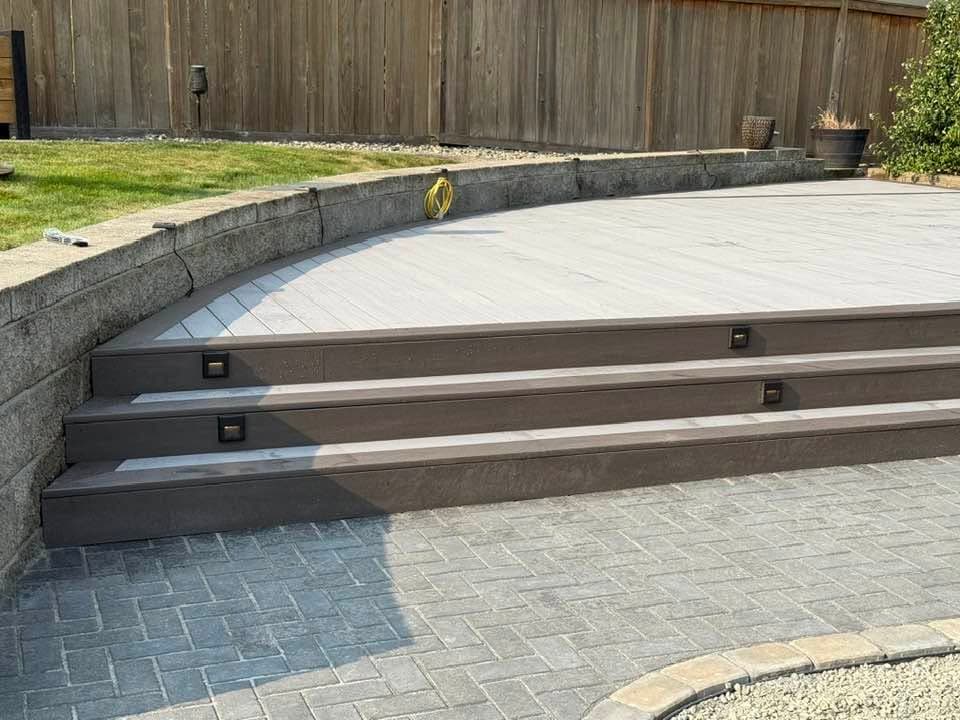Composite deck with full-width steps down to a paver patio, built by Best Pro Contractors