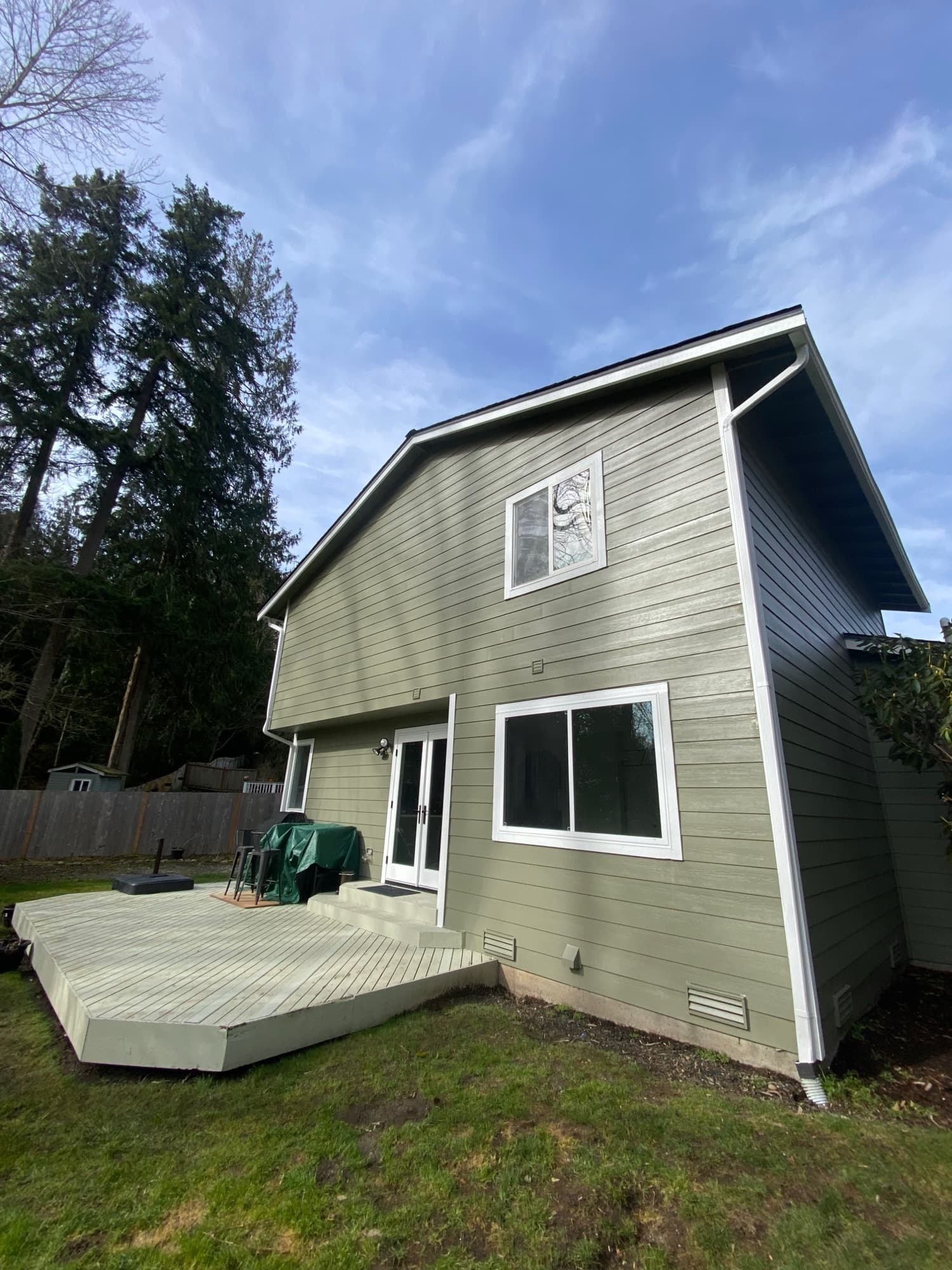 Two-storey rear elevation finished in green lap siding with white trim and new white gutters