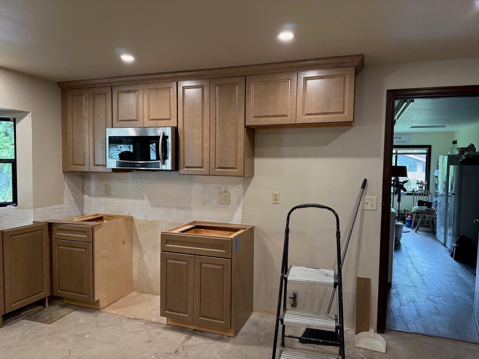 Kitchen cabinet installation in progress with upper cabinets hung and crown run, and base boxes being set
