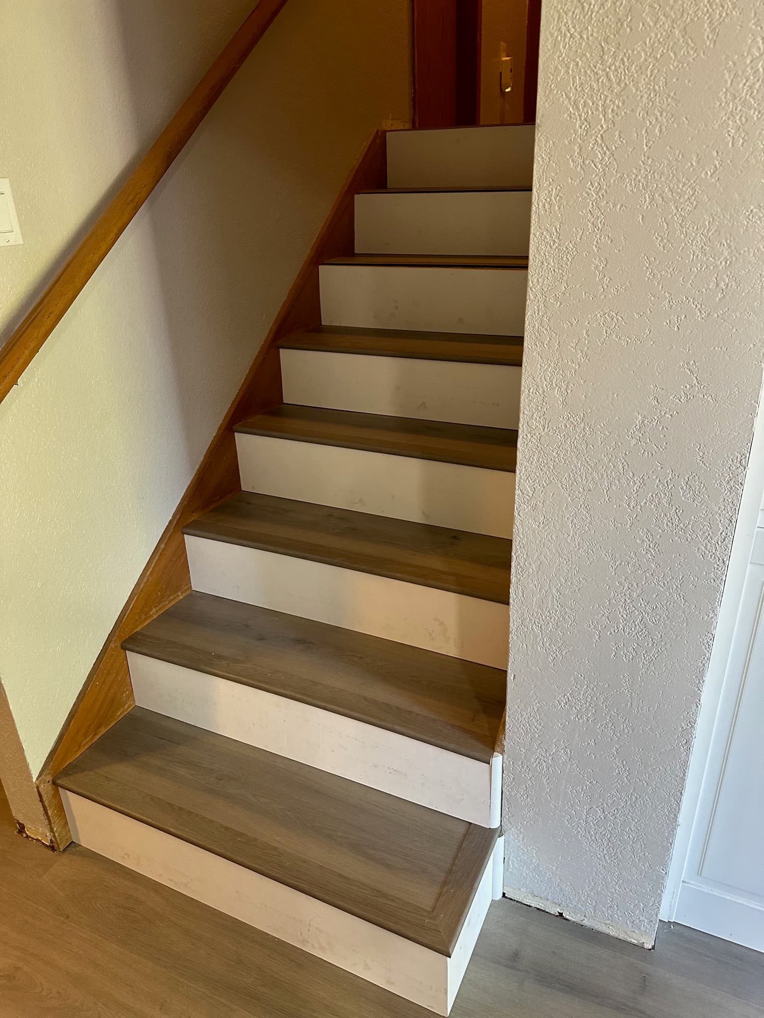 Staircase with new wood-look treads and white painted risers, matched to the flooring at the base