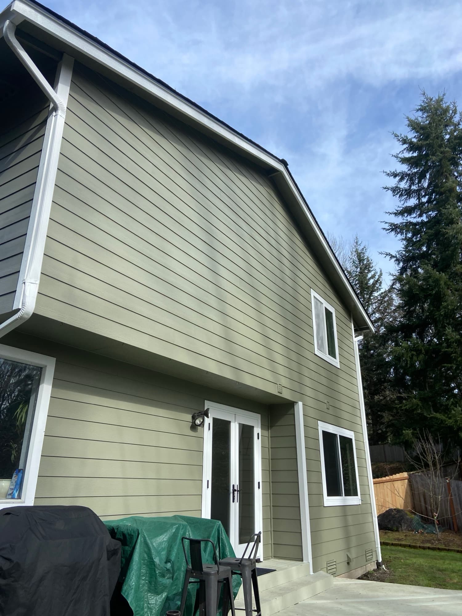 Gable end of the same house showing lap siding, trimmed window openings and a new downspout